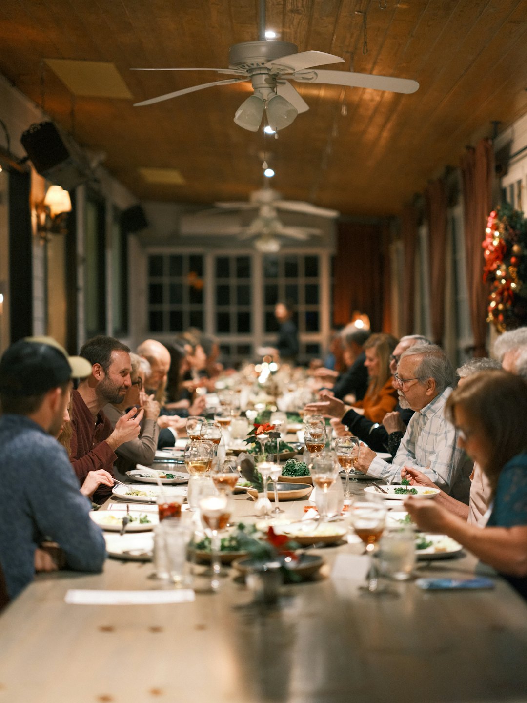 Diverse people enjoy a meal and conversation at a long table.