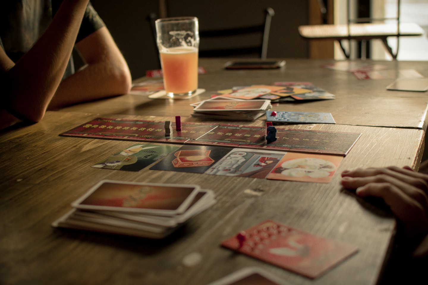 Two people playing a board game at a wooden table.