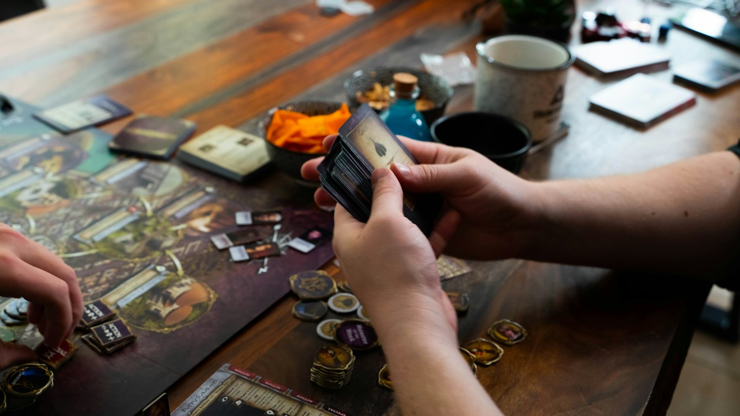 People playing a board game on a wooden table.